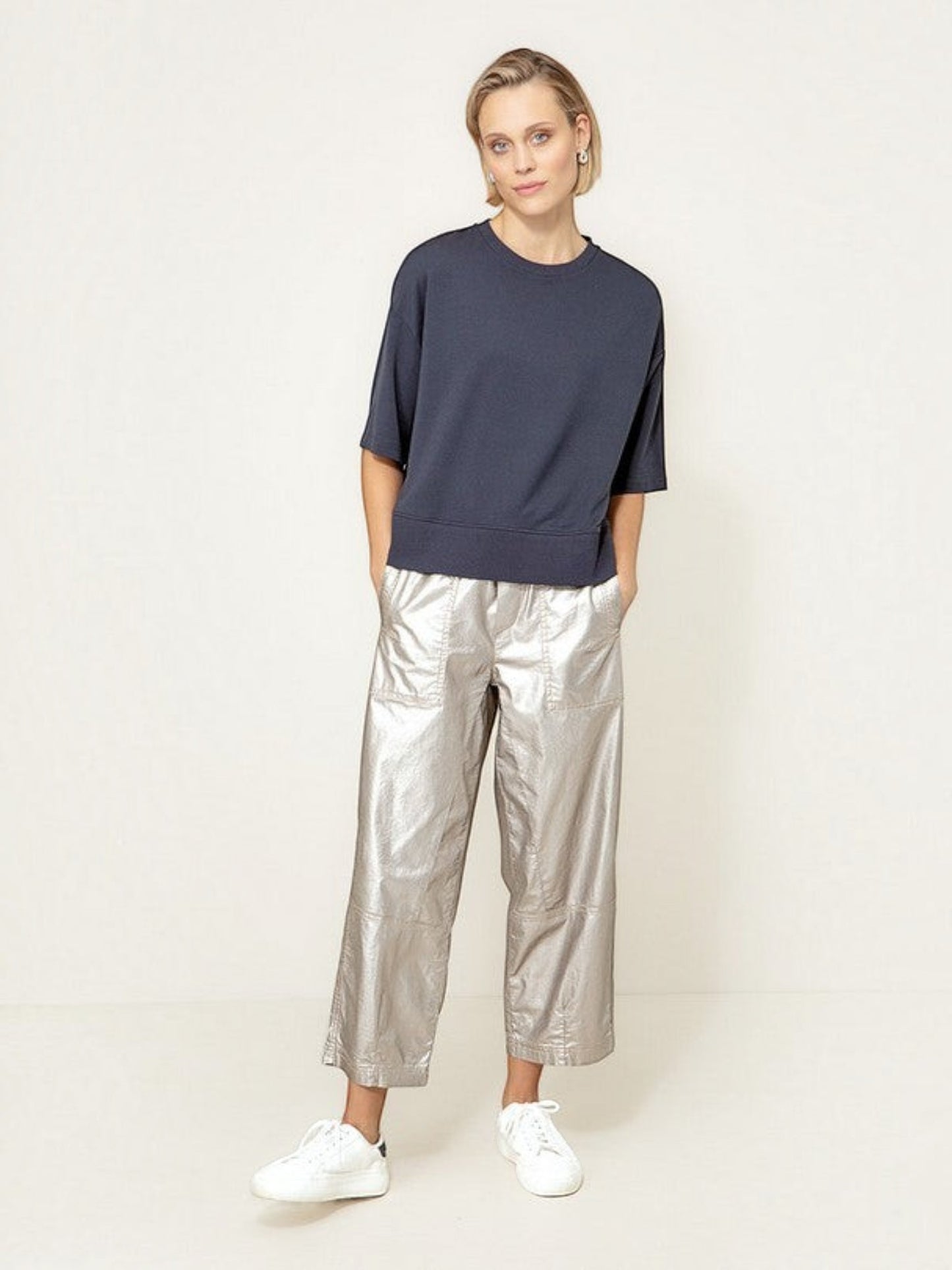 Model draagt een donkerblauw oversized T-shirt van webshop Isabelle Fashion met een zilveren broek en witte sneakers.